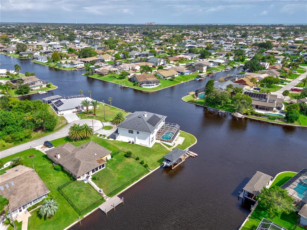 An aerial view shows waterfront houses with pools and boat docks along a canal — 16 FLORENCE COURT, PALM COAST, FL
