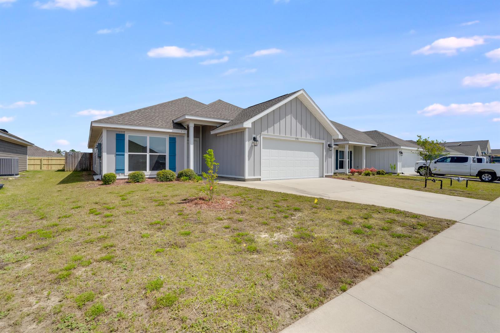A single-story house with light gray vertical siding, blue shutters, and a two-car garage — 274 Bayou Bend Lane, Panama City FL 32404, PANAMA CITY, FL