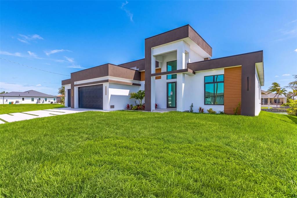 A modern, single-story house with a dark brown and white exterior and a paved driveway — 1503 NW 38 AVENUE, CAPE CORAL, FL