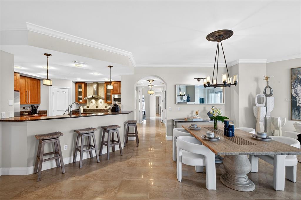A dining area with a wooden table and white chairs sits beside a kitchen island — 3703 S ATLANTIC AVENUE UNIT 204, DAYTONA BEACH SHORES, FL