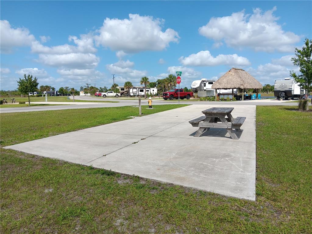 A concrete pad with a wooden picnic table sits in an outdoor RV park setting — 16950 COUNTY ROAD 630 E UNIT 107, LAKE WALES, FL