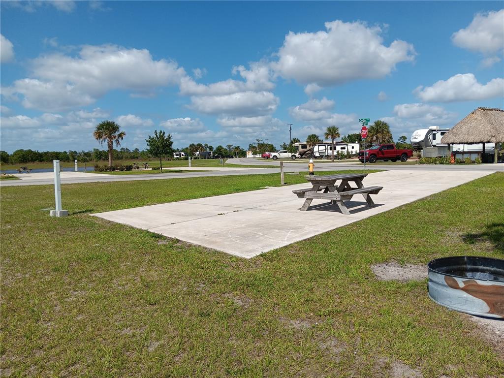 An outdoor RV campsite features a concrete pad, a picnic table, and a fire ring — 16950 COUNTY ROAD 630 E UNIT 107, LAKE WALES, FL