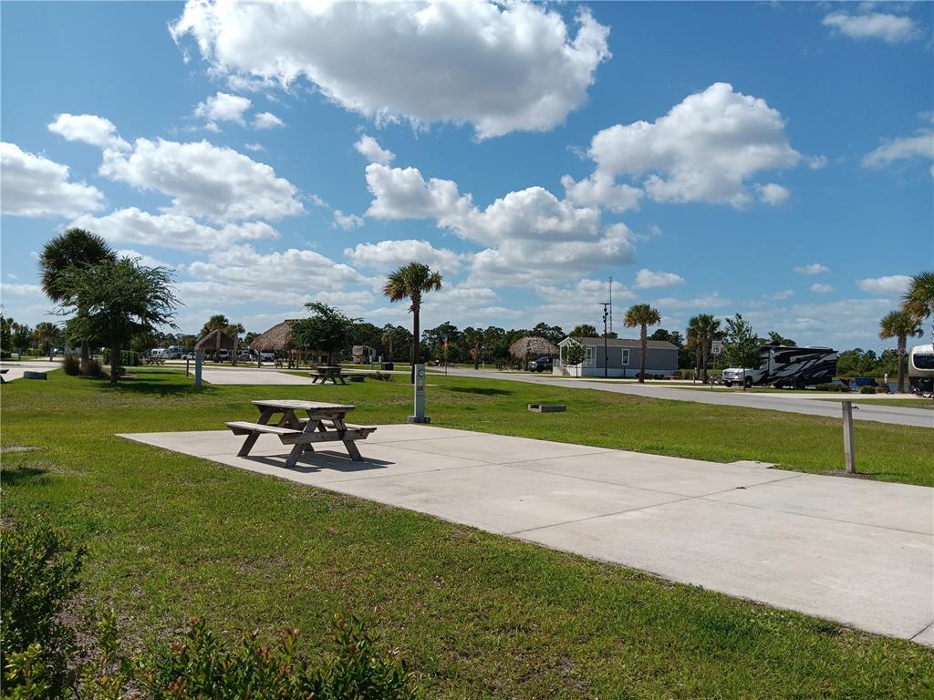 A concrete pad with a picnic table sits in a sunny, grassy RV park area — 16950 COUNTY ROAD 630 E UNIT 107, LAKE WALES, FL