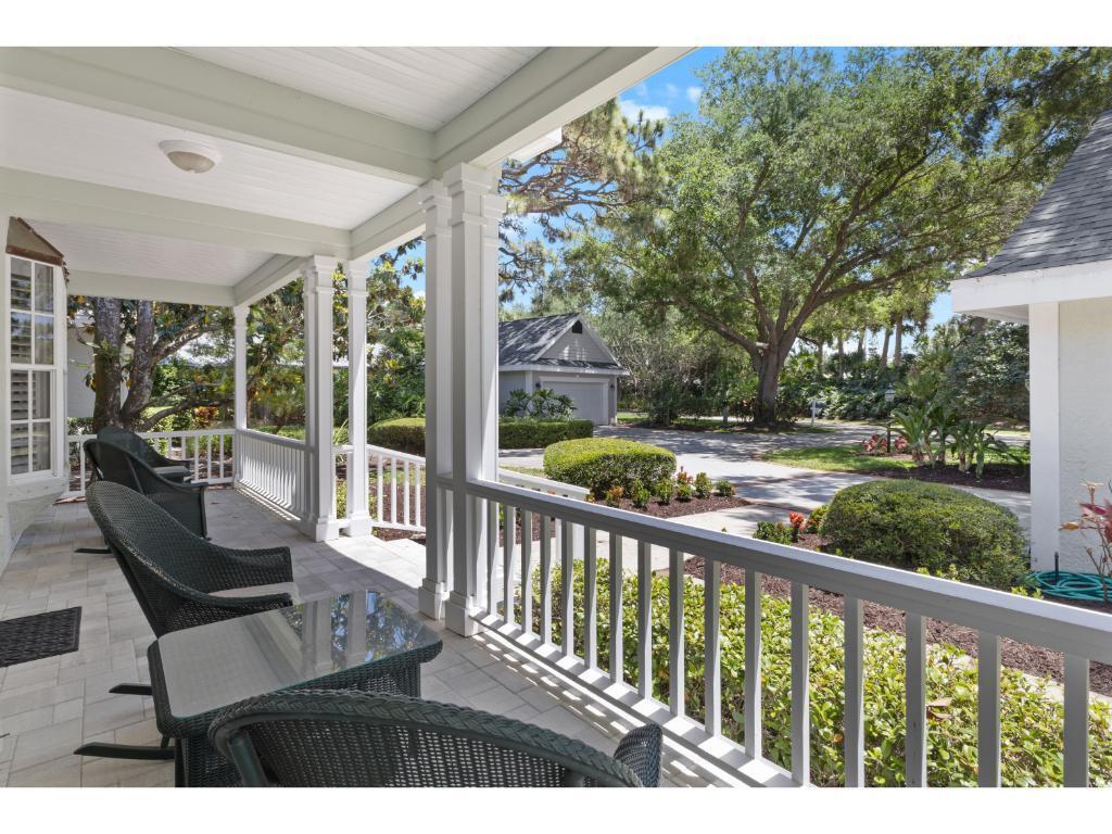 A covered porch features wicker chairs, a glass-topped table, and a view of the yard — 814 Carolina Circle SW, Vero Beach FL 32962, VERO BEACH, FL