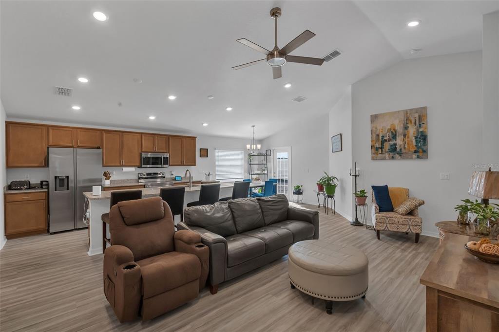 An open-concept living room and kitchen featuring wood-look flooring, a ceiling fan, and cabinetry — 4820 SE 91ST PLACE, OCALA, FL