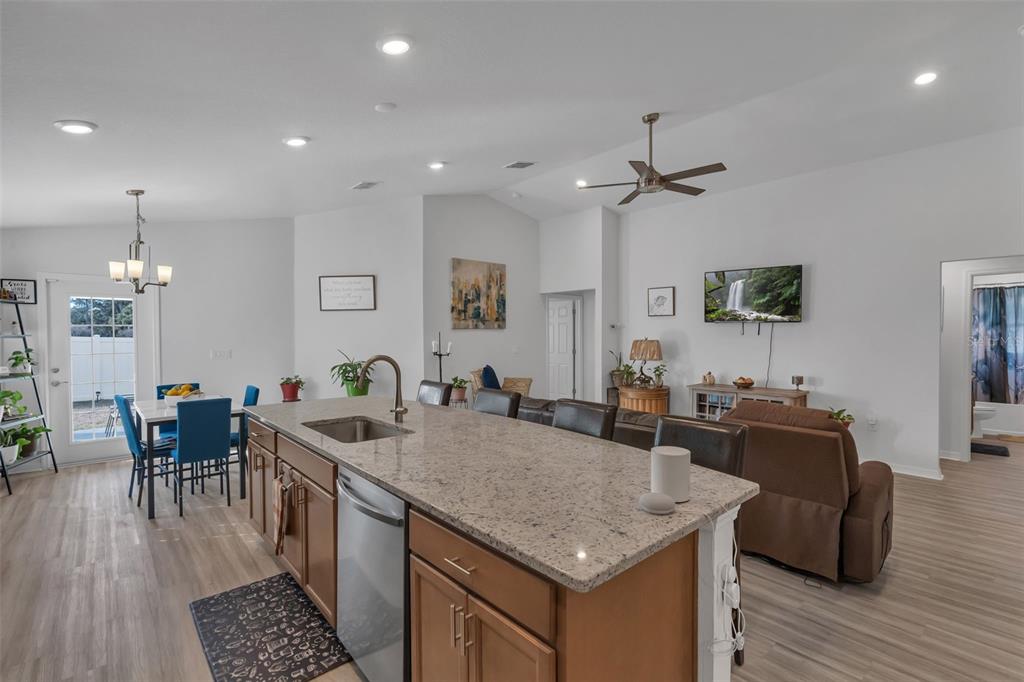 A kitchen island with granite countertops overlooks a living area with a television and sofa — 4820 SE 91ST PLACE, OCALA, FL