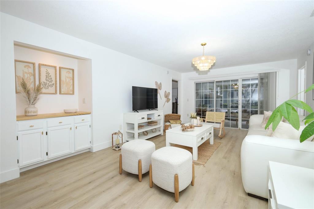 A bright living room features white cabinetry, light wood flooring, and a sliding glass door — 7102 OLYMPIA COURT UNIT 7102, LONGWOOD, FL