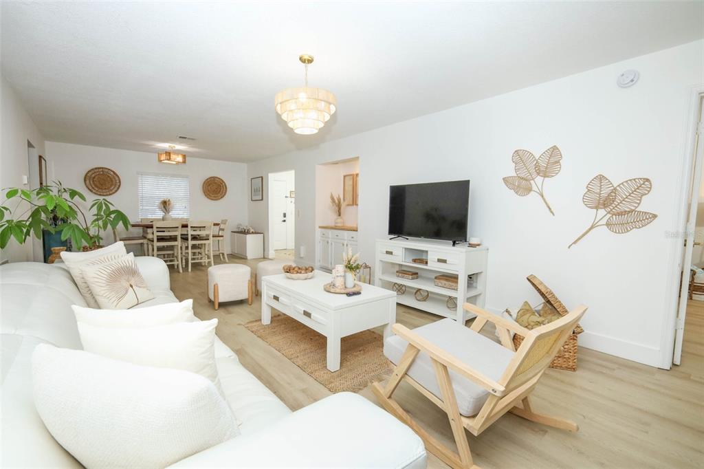 A bright living room features white furniture, a wooden rocking chair, and light wood flooring — 7102 OLYMPIA COURT UNIT 7102, LONGWOOD, FL