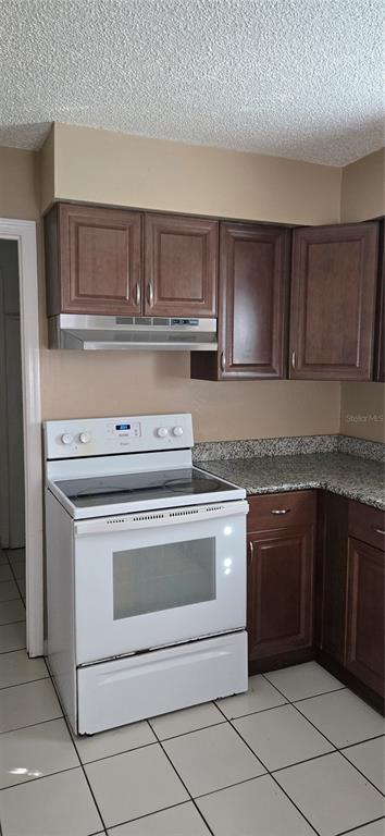 A kitchen features dark wood cabinets, a white electric stove, and granite countertops — 2530 GEORGIA AVENUE UNIT B, SANFORD, FL
