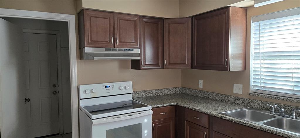 A kitchen features dark wood cabinets, granite countertops, a white stove, and a double sink — 2530 GEORGIA AVENUE UNIT B, SANFORD, FL