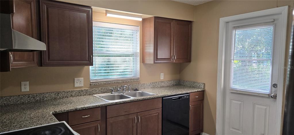 A kitchen features dark wood cabinets, granite countertops, a double sink, and a glass-paneled door — 2530 GEORGIA AVENUE UNIT B, SANFORD, FL