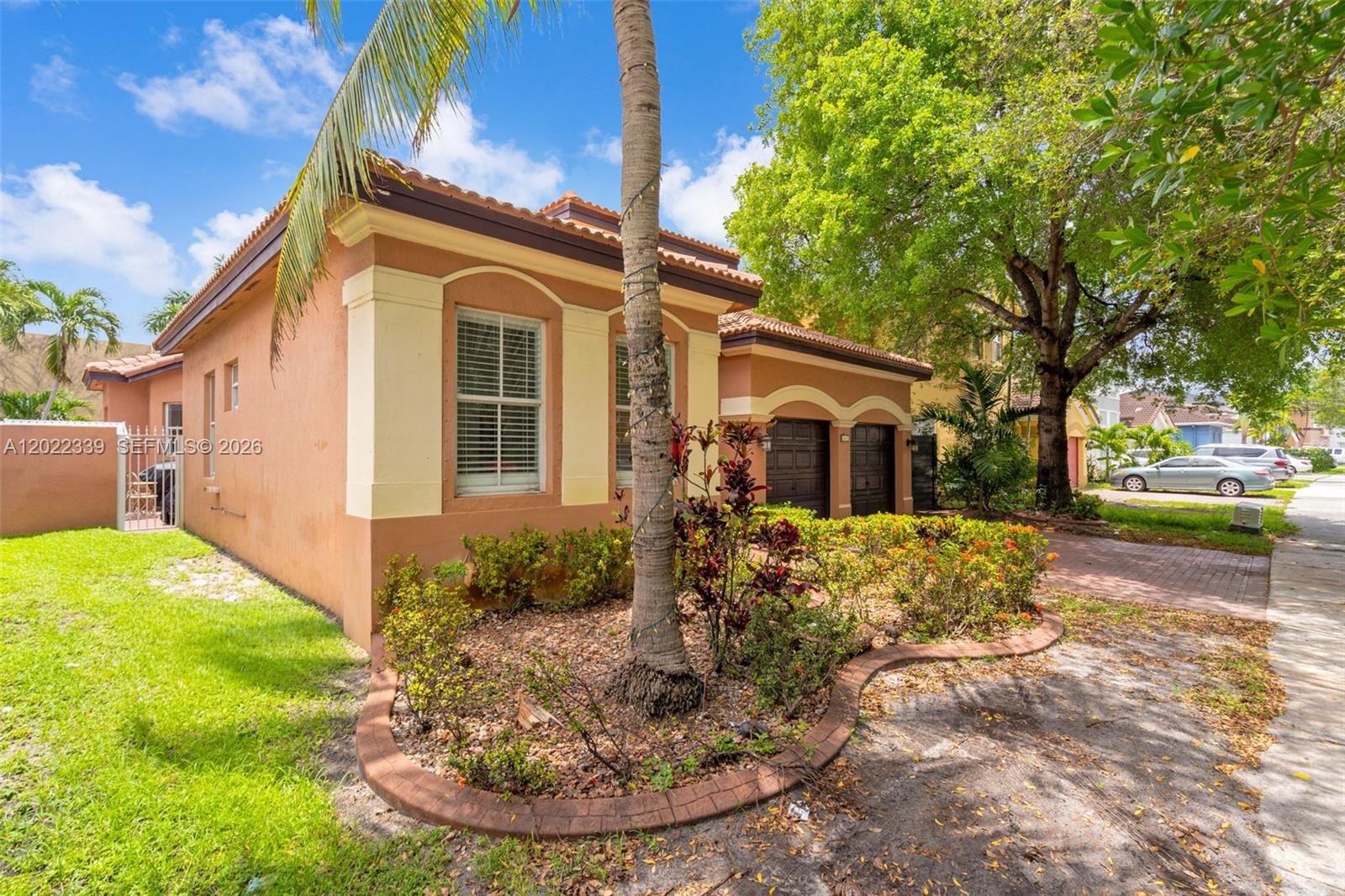 A tan stucco house with a tiled roof, a palm tree, and a brick driveway — 18122 NW 91st Ct, Hialeah FL 33018, HIALEAH, FL