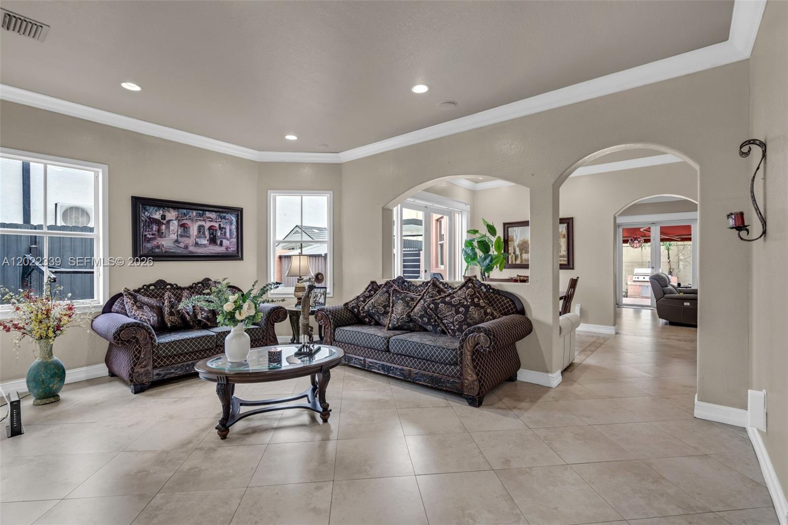 A living room features tile flooring, two dark patterned sofas, and arched wall openings — 18122 NW 91st Ct, Hialeah FL 33018, HIALEAH, FL