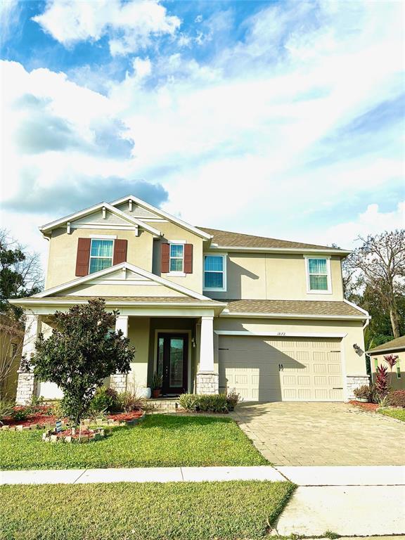 A two-story suburban house features a tan stucco exterior, a front porch, and a garage — 1872 IBIS BAY COURT, OCOEE, FL