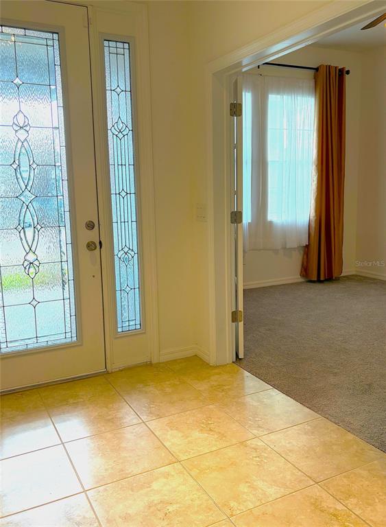An entryway with tiled floors leads to a carpeted room through a set of French doors — 1872 IBIS BAY COURT, OCOEE, FL