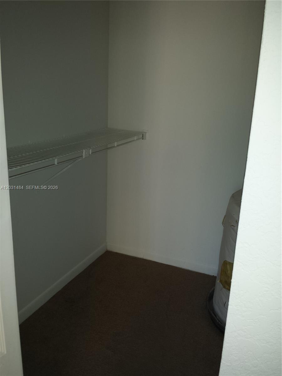 A small walk-in closet features a single wire shelf and carpeted flooring — 8160 GENEVA WY # 316, Miami FL 33166, MIAMI, FL