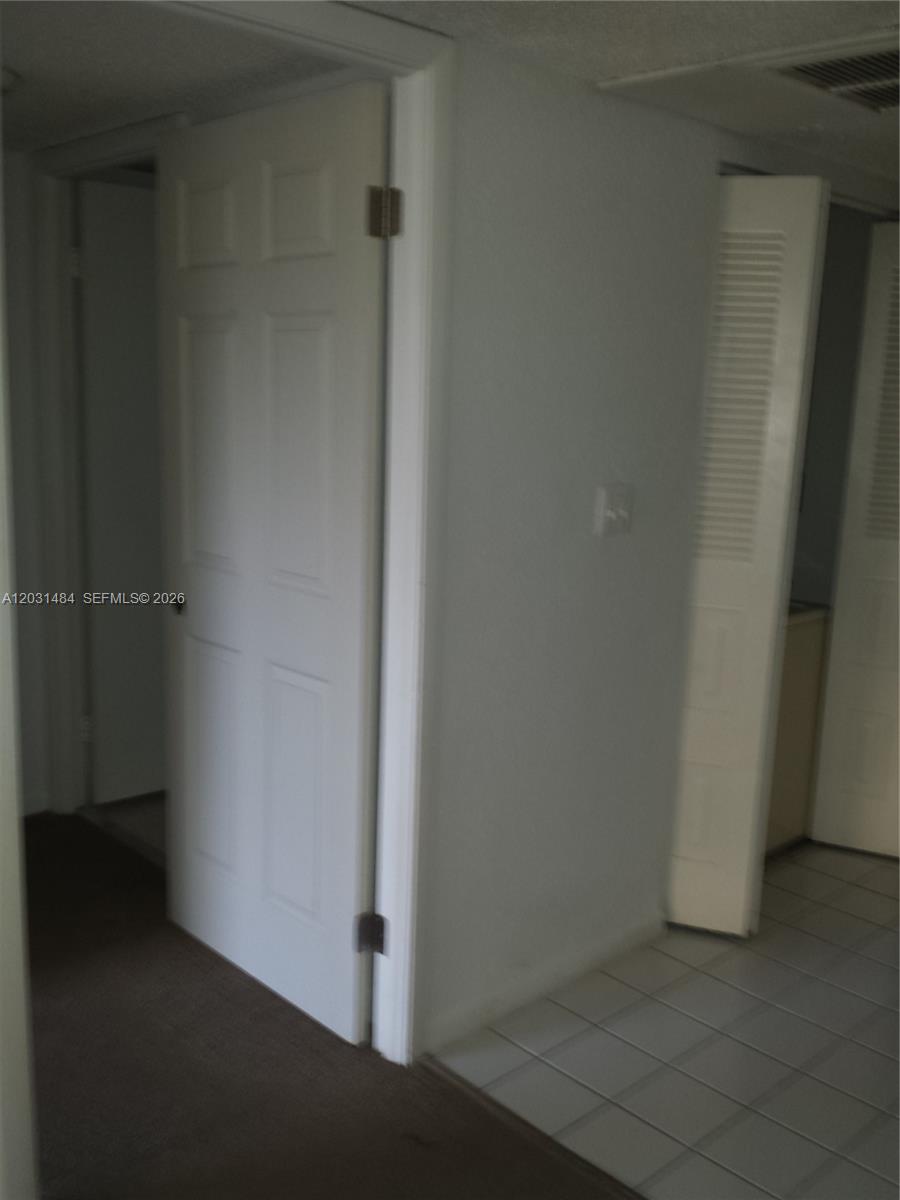 A hallway features a white door, a louvered closet door, and a mix of carpeted and tiled flooring — 8160 GENEVA WY # 316, Miami FL 33166, MIAMI, FL