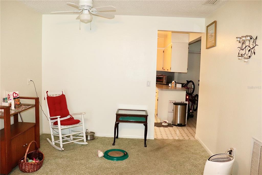 A carpeted room features a white rocking chair, a small table, and a ceiling fan — 6990 VERSAILLES N UNIT 6990, PINELLAS PARK, FL