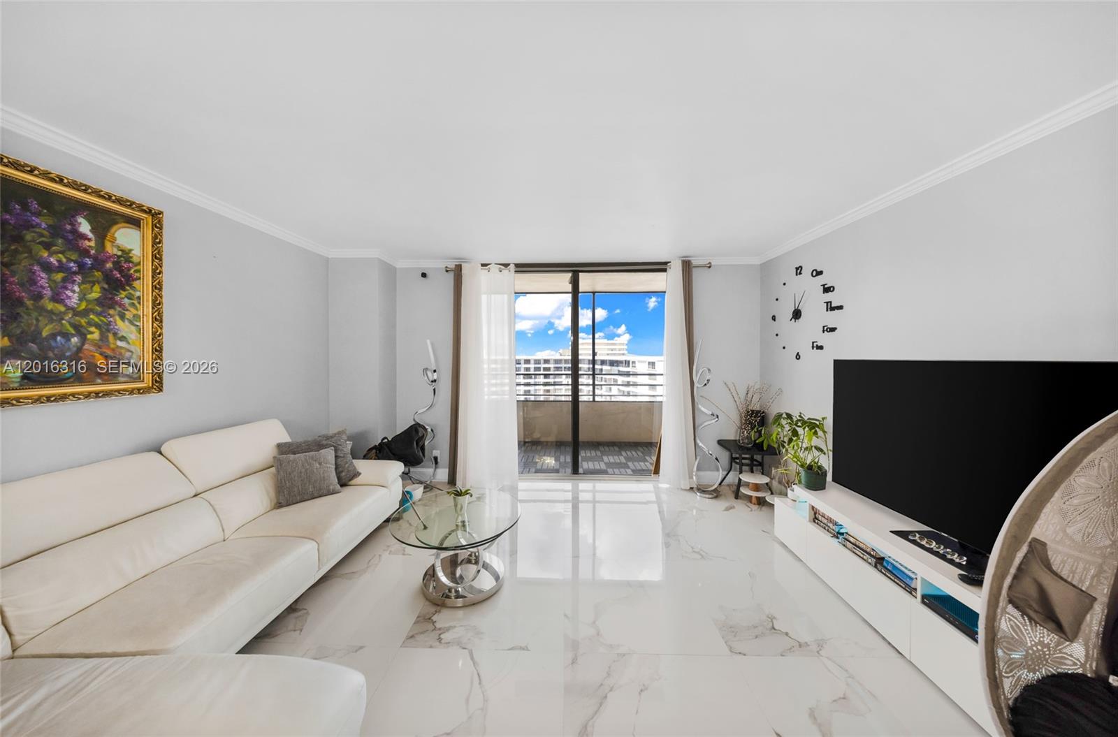 A living room features white tile flooring, a white sofa, a television, and a balcony — 2500 Parkview Dr # 2119, Hallandale Beach FL 33009, HALLANDALE BEACH, FL