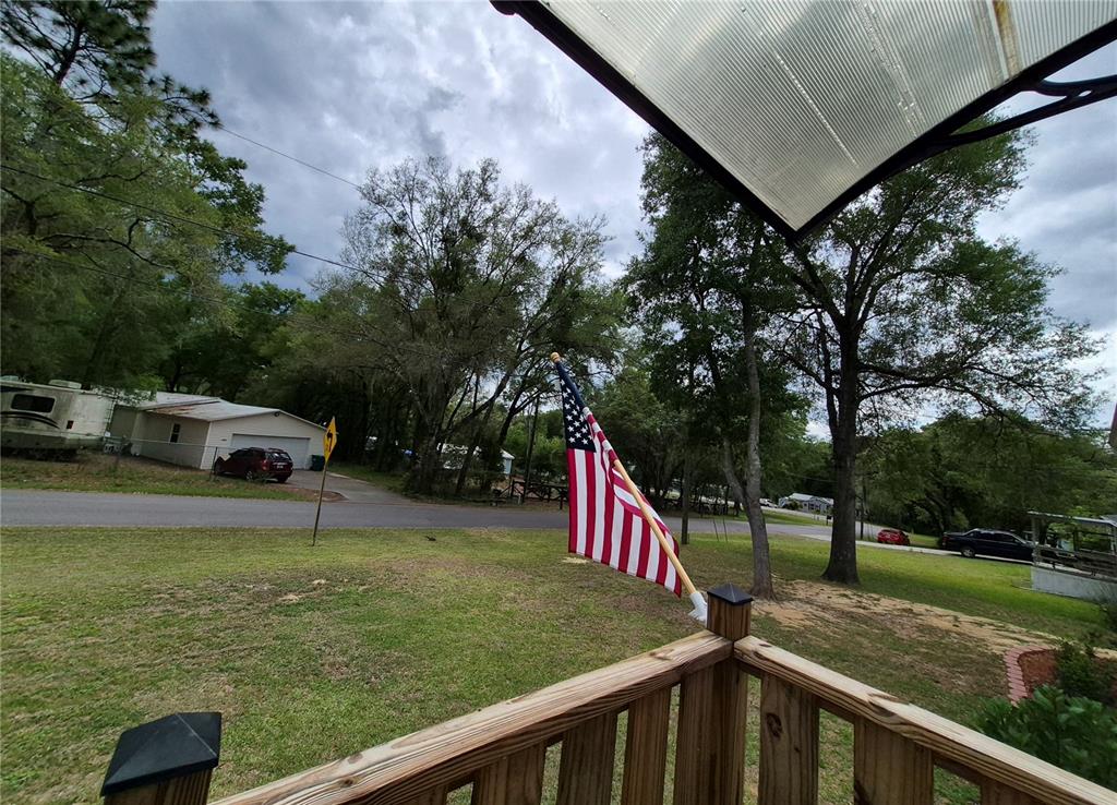 A view from a wooden porch looking out toward a yard, trees, and a road — 2521 E MERCURY STREET, INVERNESS, FL
