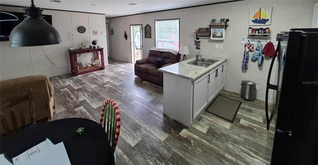 A kitchen island with a sink sits in an open-concept living area with wood-look flooring — 2521 E MERCURY STREET, INVERNESS, FL