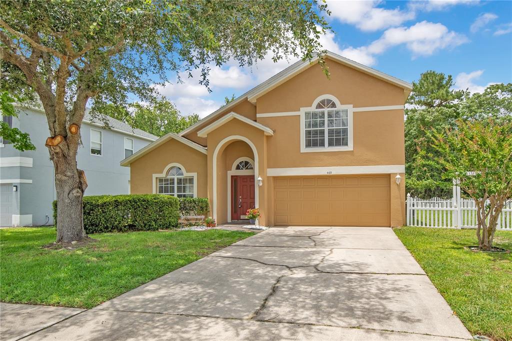 A two-story tan house with a front-facing garage and a concrete driveway — 469 CAREY WAY, ORLANDO, FL