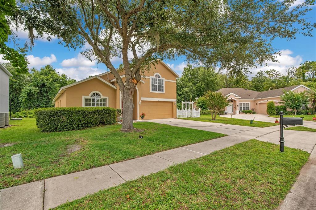 A two-story tan house with a two-car garage and a large tree in the yard — 469 CAREY WAY, ORLANDO, FL
