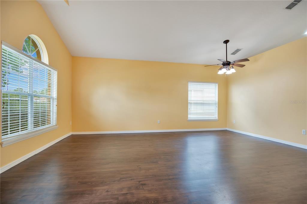 An empty living room features yellow walls, dark wood-look flooring, and a ceiling fan — 469 CAREY WAY, ORLANDO, FL
