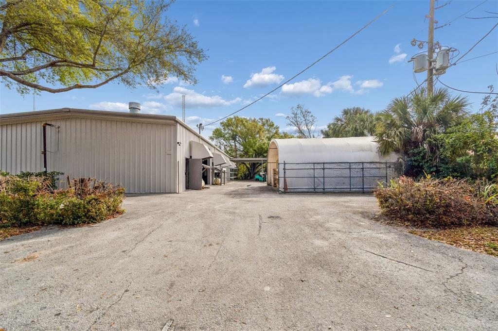 An exterior view shows a metal warehouse building next to a fenced, fabric-covered storage structure — 1060 HARBOR LAKE DRIVE, SAFETY HARBOR, FL