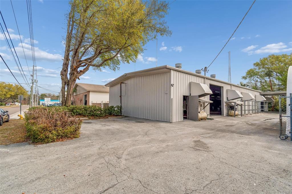A metal-sided commercial building stands next to a paved parking lot and a large tree — 1060 HARBOR LAKE DRIVE, SAFETY HARBOR, FL