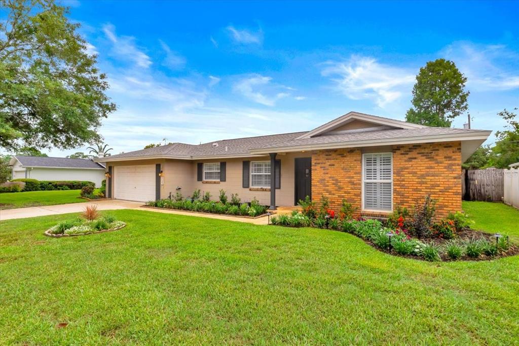 A single-story house with a brick facade, beige siding, a two-car garage, and landscaped lawn — 715 S RANGER BOULEVARD, WINTER PARK, FL
