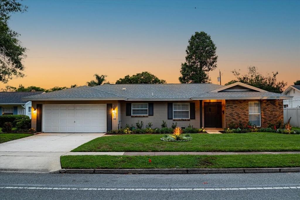 A single-story house with a brick facade, a two-car garage, and a landscaped front lawn — 715 S RANGER BOULEVARD, WINTER PARK, FL