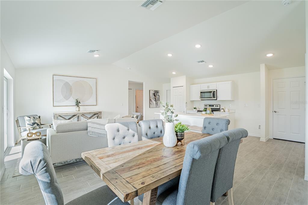 An open-concept living and dining area features a wooden table, gray chairs, and a kitchen — 2035 BROAD RANCH DRIVE, PORT CHARLOTTE, FL