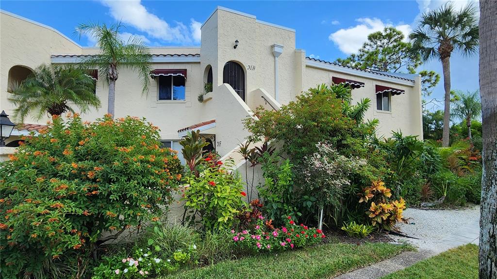 A two-story stucco building features a central staircase, arched entryway, and lush landscaping — 6101 34TH STREET W UNIT 31H, BRADENTON, FL