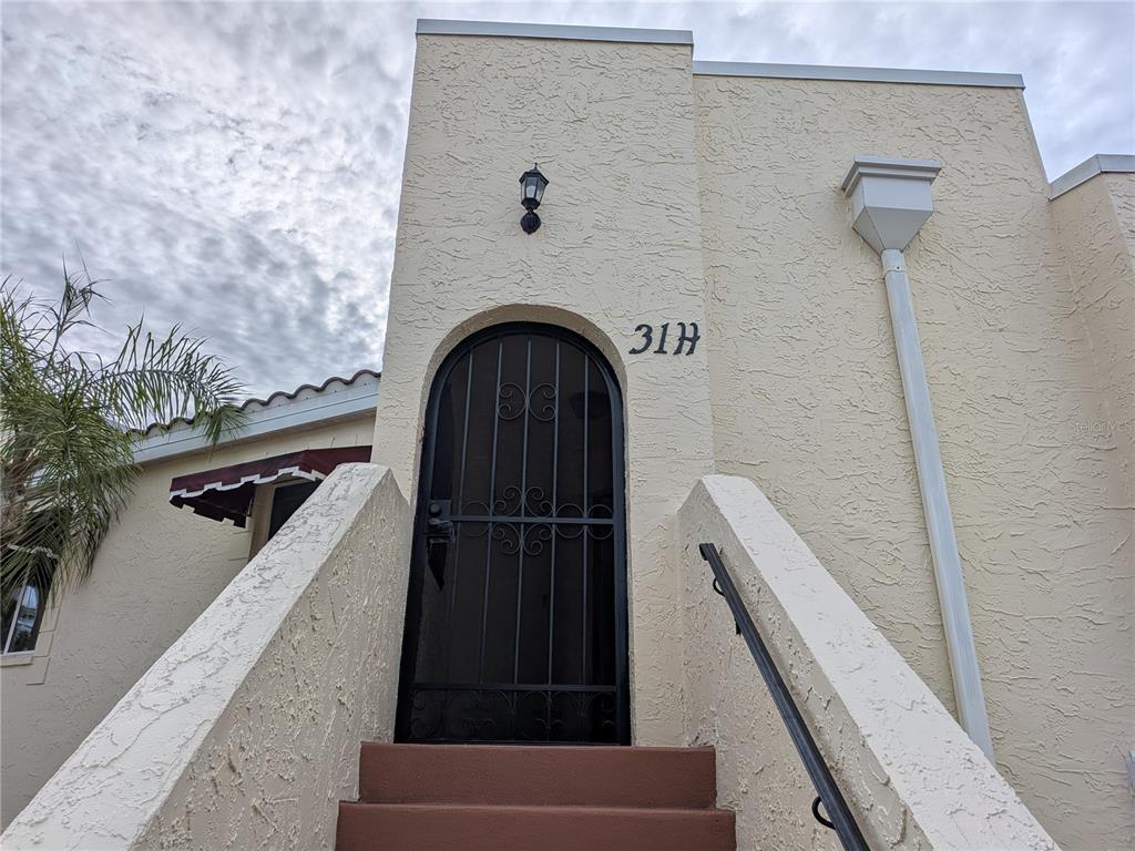 An exterior view of a building entrance with a metal security door and stairs — 6101 34TH STREET W UNIT 31H, BRADENTON, FL