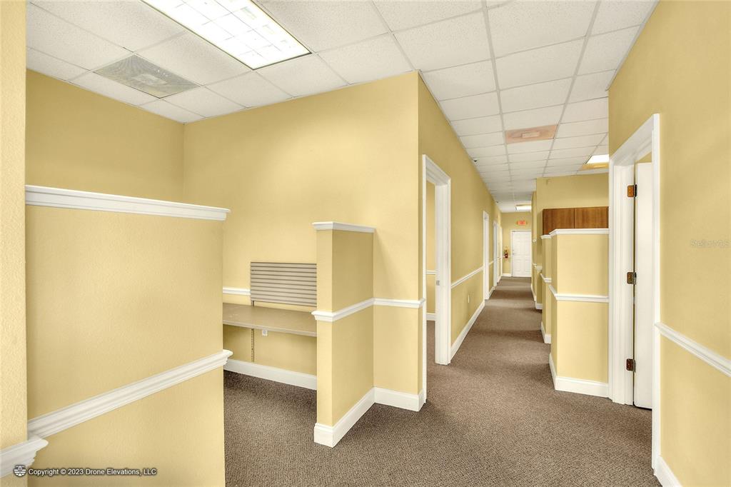 A hallway with yellow walls, carpeted floors, and several open-concept office cubicles — 657 W LUMSDEN ROAD, BRANDON, FL