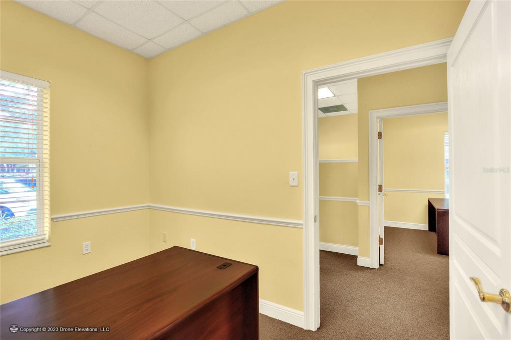 A small office with yellow walls, a brown desk, and a doorway leading to another room — 657 W LUMSDEN ROAD, BRANDON, FL