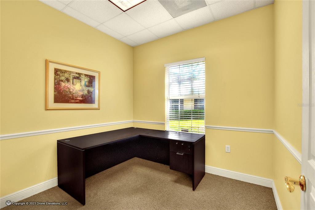 A small office with yellow walls, tan carpet, a dark L-shaped desk, and a window — 657 W LUMSDEN ROAD, BRANDON, FL