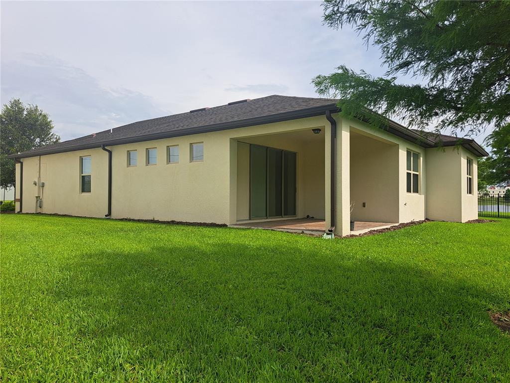 The exterior of a beige stucco house features a covered patio and a grassy yard — 2501 CIVITAS PLACE, CASSELBERRY, FL