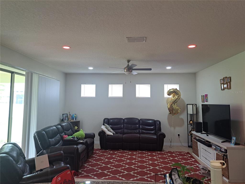 A living room features dark leather sofas, a red patterned rug, and four small windows — 2501 CIVITAS PLACE, CASSELBERRY, FL