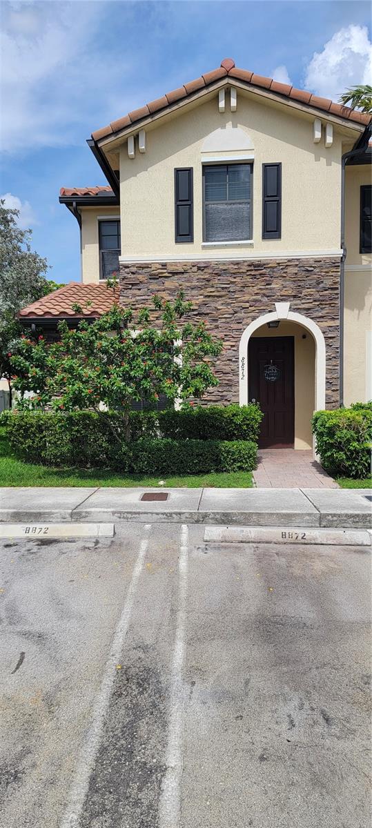 A two-story townhouse features a stone facade, a brown front door, and two parking spaces — 8872 W 35th Ct, Hialeah FL 33018, HIALEAH, FL