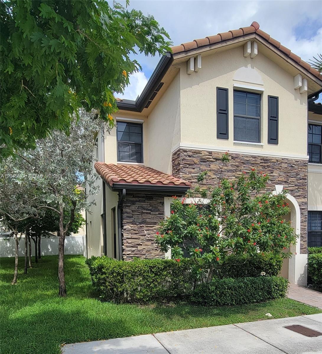 A two-story house exterior features tan stucco, stone veneer siding, and a terracotta tile roof — 8872 W 35th Ct, Hialeah FL 33018, HIALEAH, FL