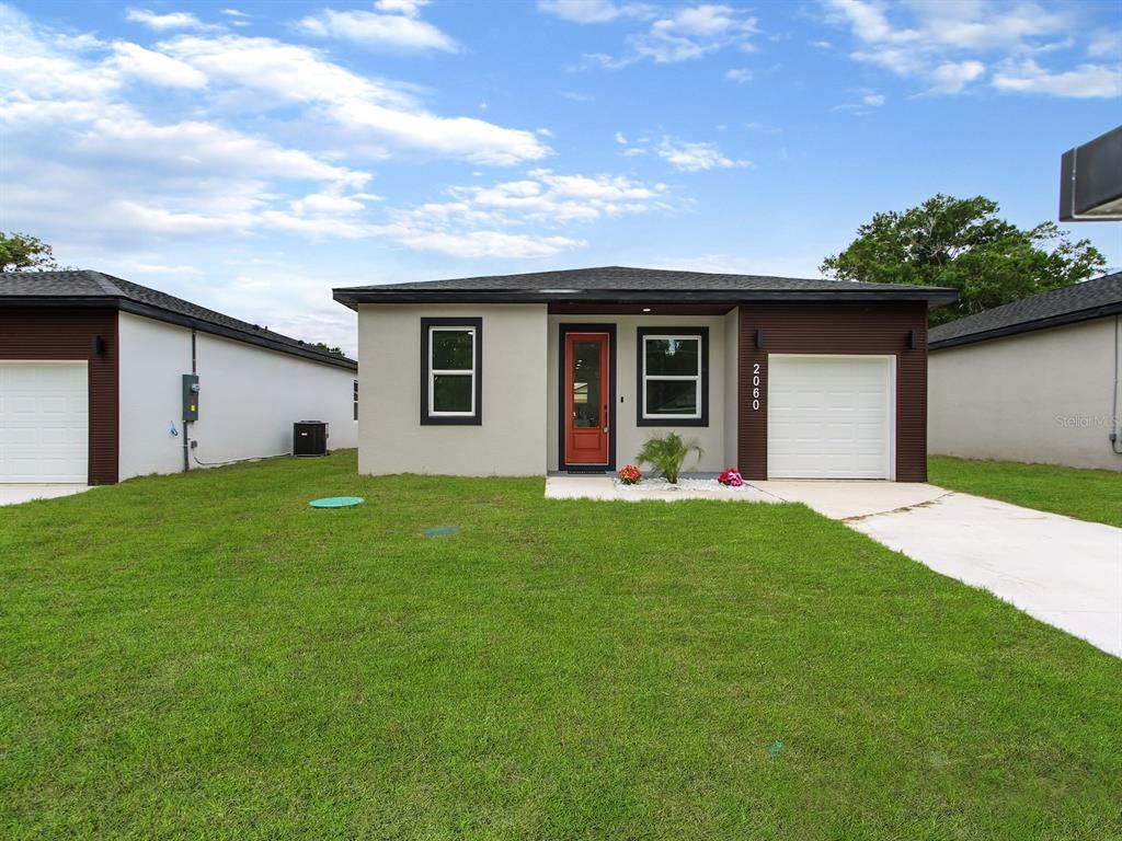 A single-story house with a beige exterior, dark trim, and a red front door — 2060 DIXIE AVENUE, SANFORD, FL