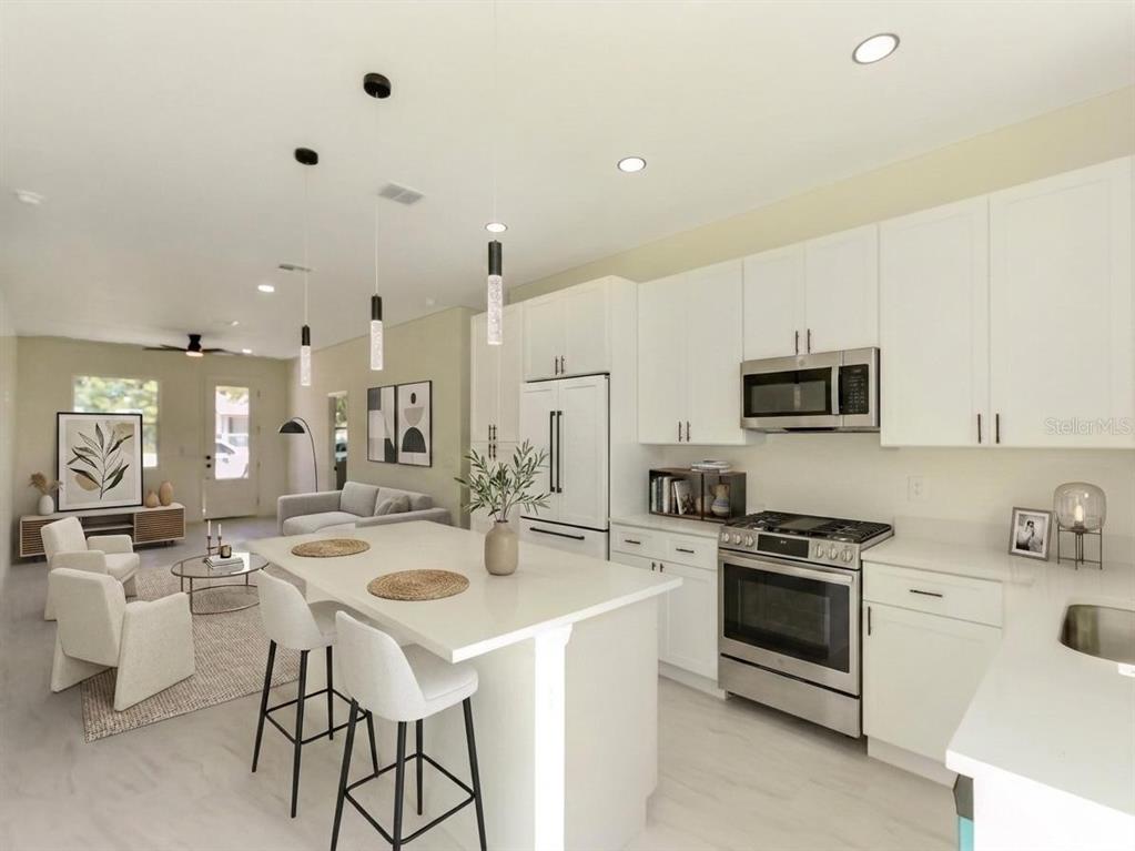 A modern kitchen with white cabinets and an island opens into a living room area — 2060 DIXIE AVENUE, SANFORD, FL