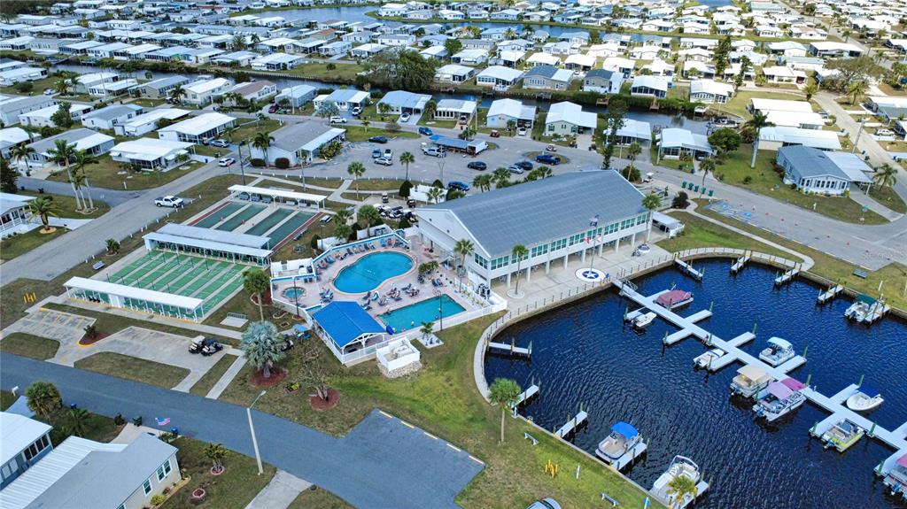 An aerial view shows a community clubhouse with a pool, boat docks, and shuffleboard courts — 530 PARKWOOD AVENUE, NORTH PORT, FL