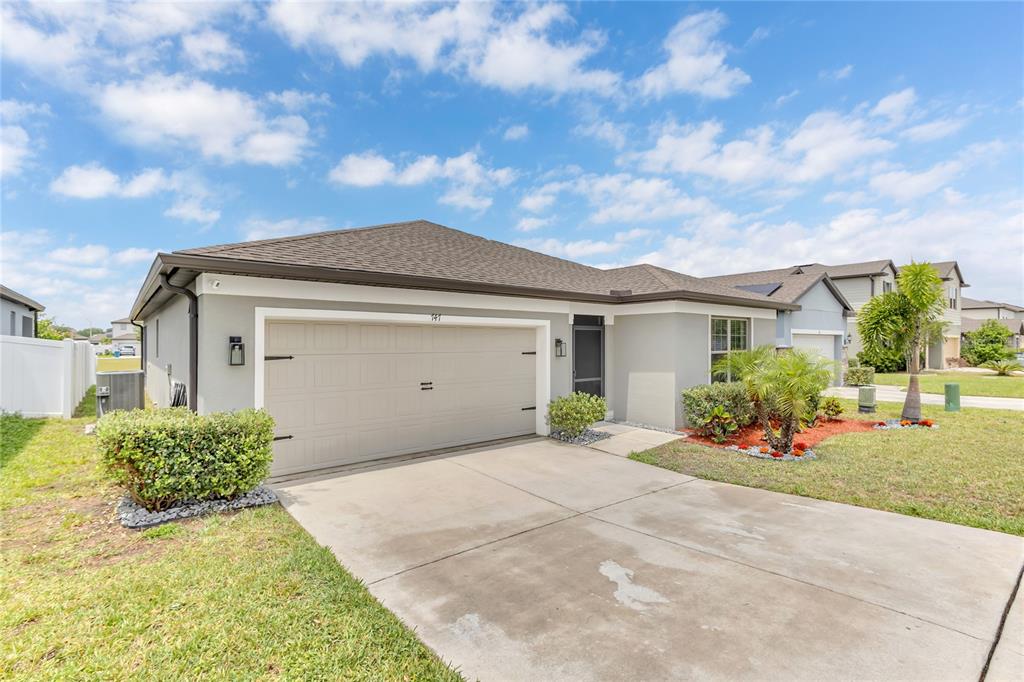 A single-story house with a two-car garage, concrete driveway, and landscaped front yard — 747 CITRUS ISLE DRIVE, DAVENPORT, FL