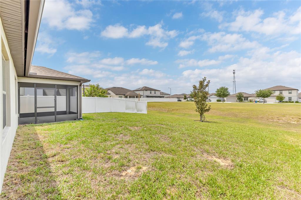 A backyard with a screened-in porch, a white vinyl fence, and a grassy lawn — 747 CITRUS ISLE DRIVE, DAVENPORT, FL