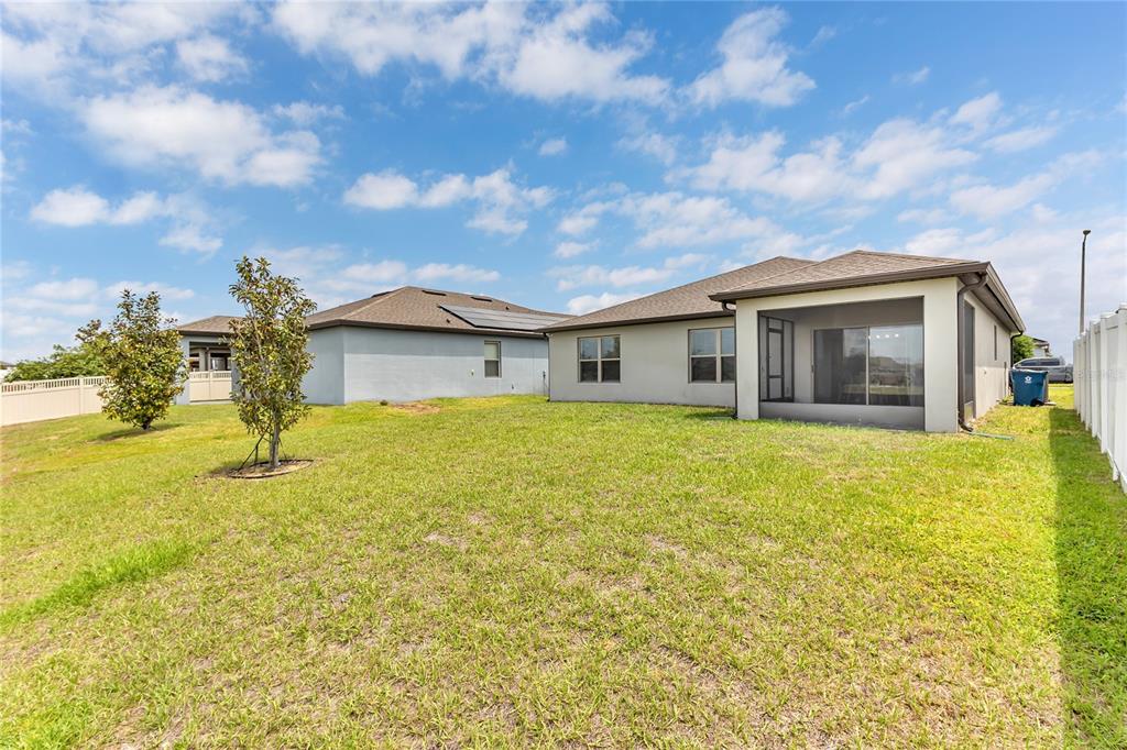 The backyard of a suburban house features a screened-in patio and a white vinyl fence — 747 CITRUS ISLE DRIVE, DAVENPORT, FL
