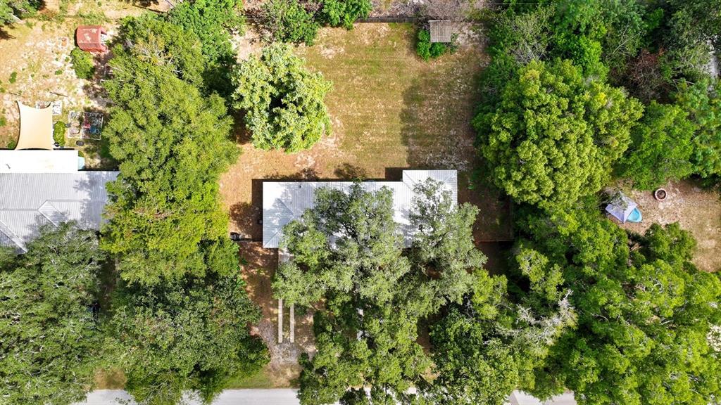 An aerial view shows a house with a metal roof surrounded by many mature trees — 130 SW PEACH STREET, KEYSTONE HEIGHTS, FL