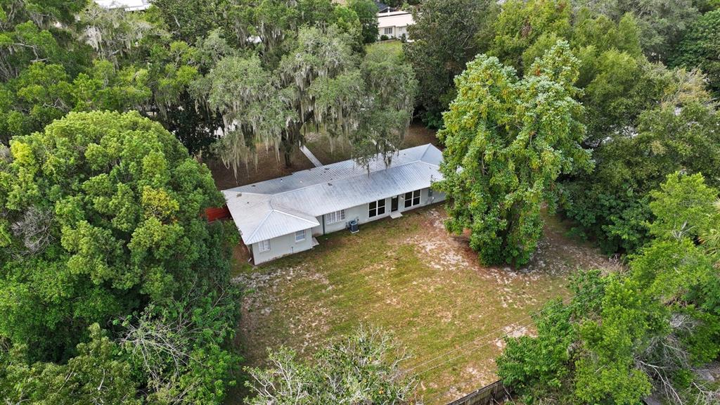 An aerial view shows a single-story house with a metal roof surrounded by dense trees — 130 SW PEACH STREET, KEYSTONE HEIGHTS, FL